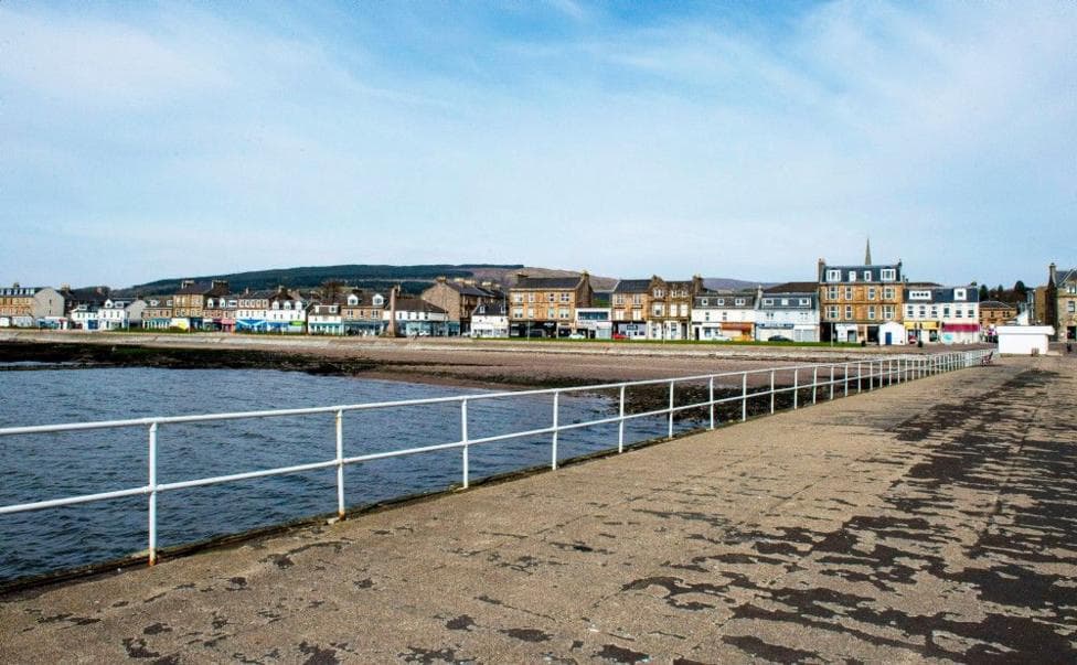 A view of the waterfront at Helensburgh, showing shops and cafes. The picture has been taken from a pier, with a fence in front of it.