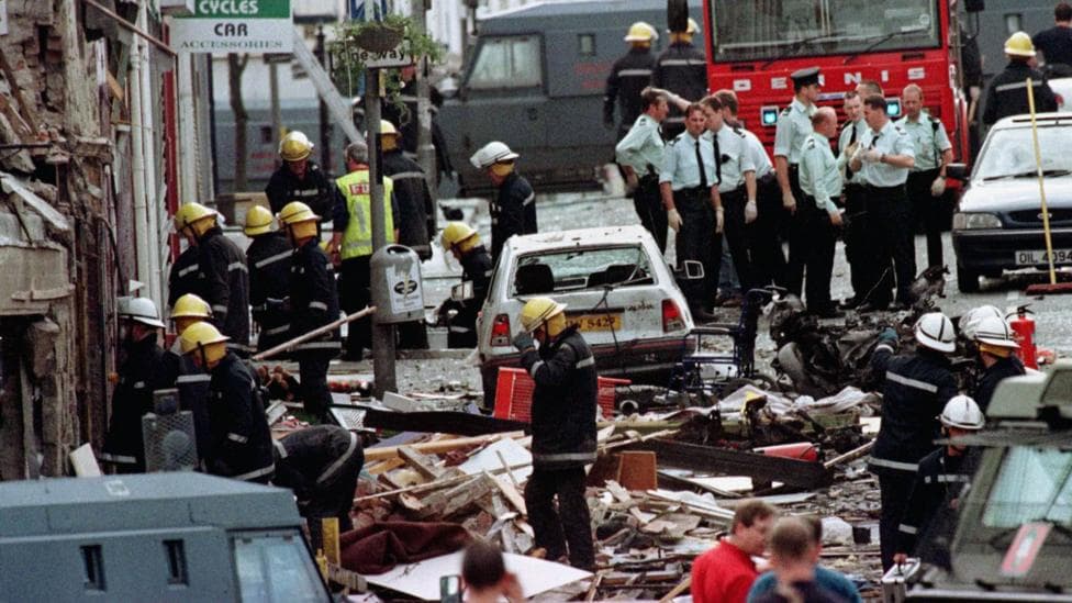 The picture shows police officers, firefighters and members of the public amidst the destruction of the Omagh bomb in the town centre in 1998