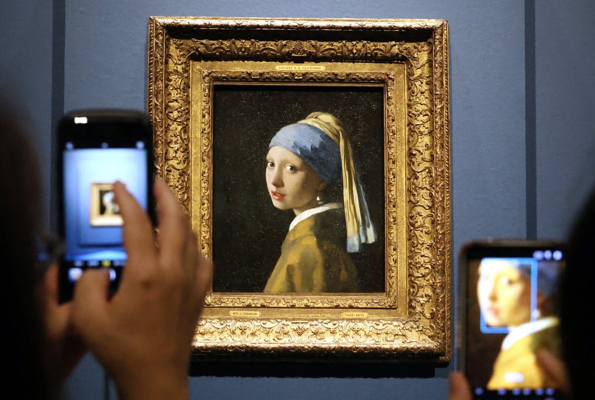 Visitors photograph Vermeer's Girl with a Pearl Earring on their phones at an exhibition