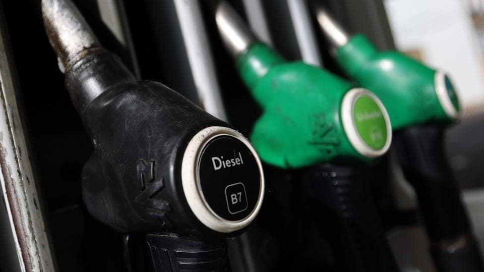 A picture of fuel pumps at a petrol station. The black diesel pump is at the front of the image in focus.