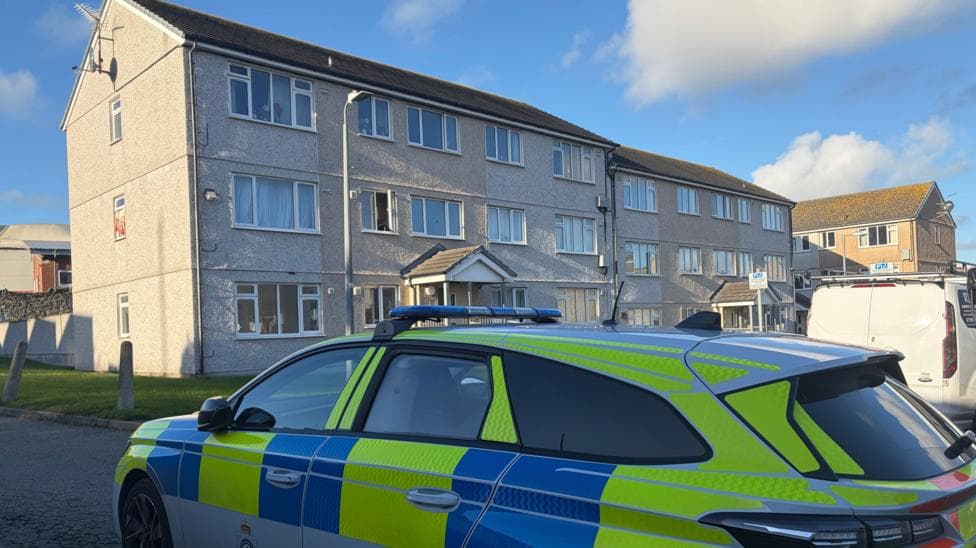 A police care parked on a residential street in front of a block of flats