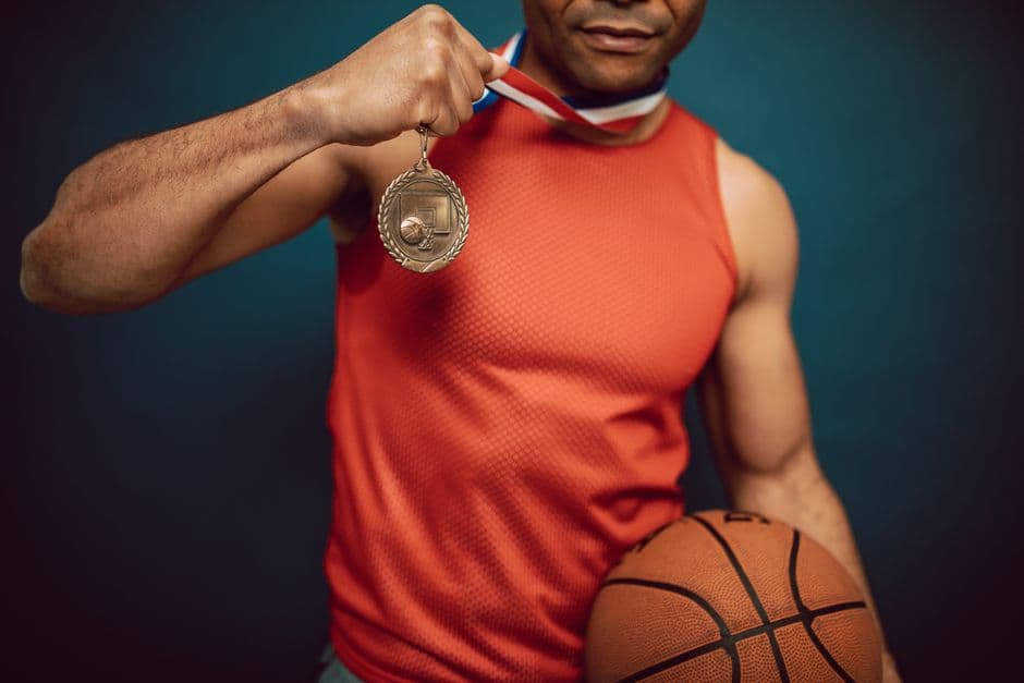 Man holding a medal and basketball, showcasing achievement in sports.
