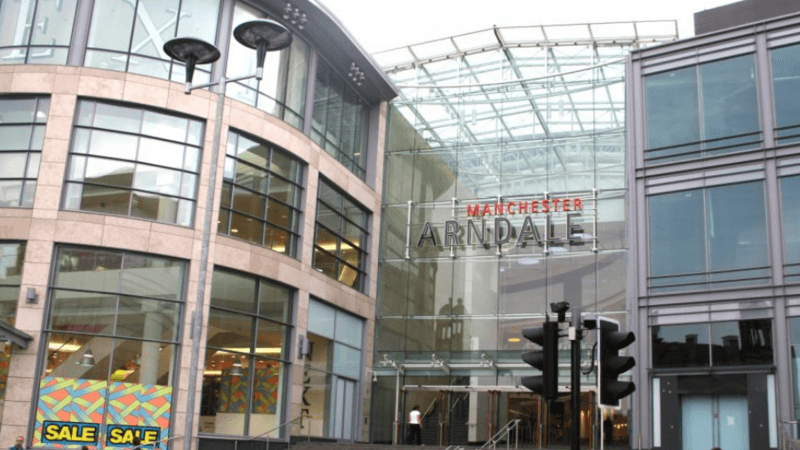 A woman walks in front of the glass-fronted Manchester Arndale shopping centre