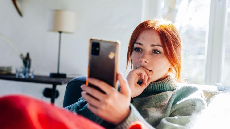 Close up of a young woman in a jumper looking at her mobile phone