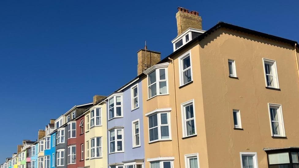 A row of colourful terraced houses under a bright blue sky.