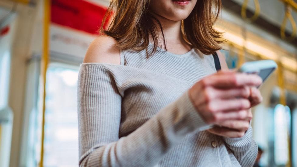 A woman holding a smartphone on a bus
