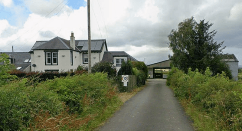 The exterior of a farm at the end of a lane. A house and barn are in the middle ground