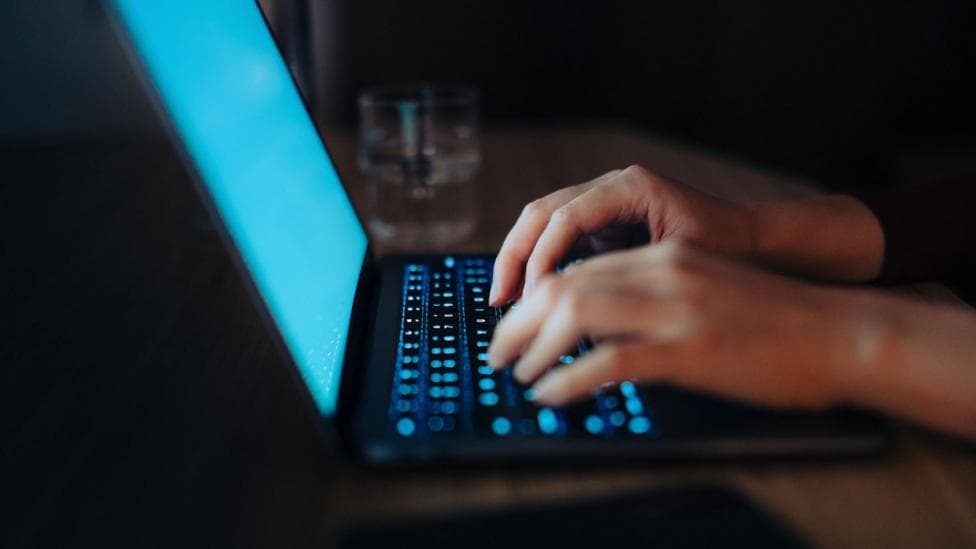 a unidentified persons hands typing on a laptop keyboard
