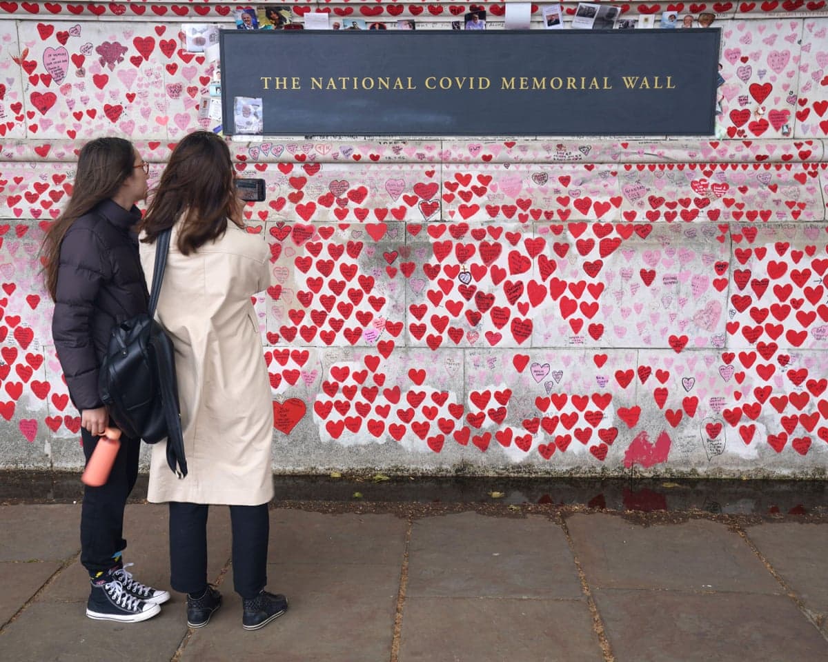 Two women view hearts covering the National Covid Memorial Wall in London