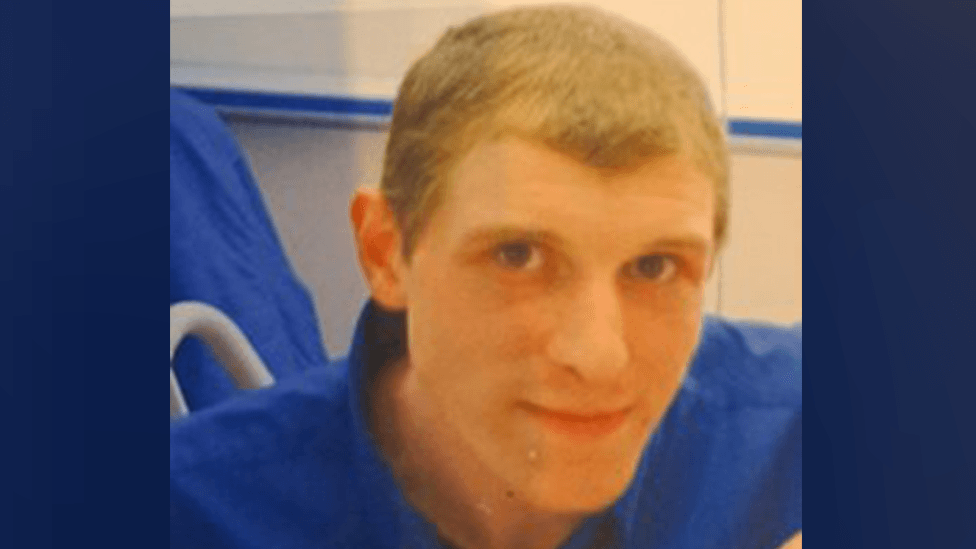 Steven Dick has short, blonde hair and is wearing a blue T-shirt.