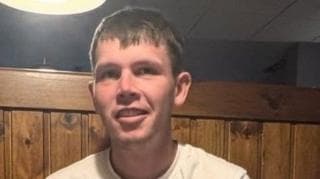 Dylan McCann. He is wearing a light-coloured top, brunette hair and is smiling.