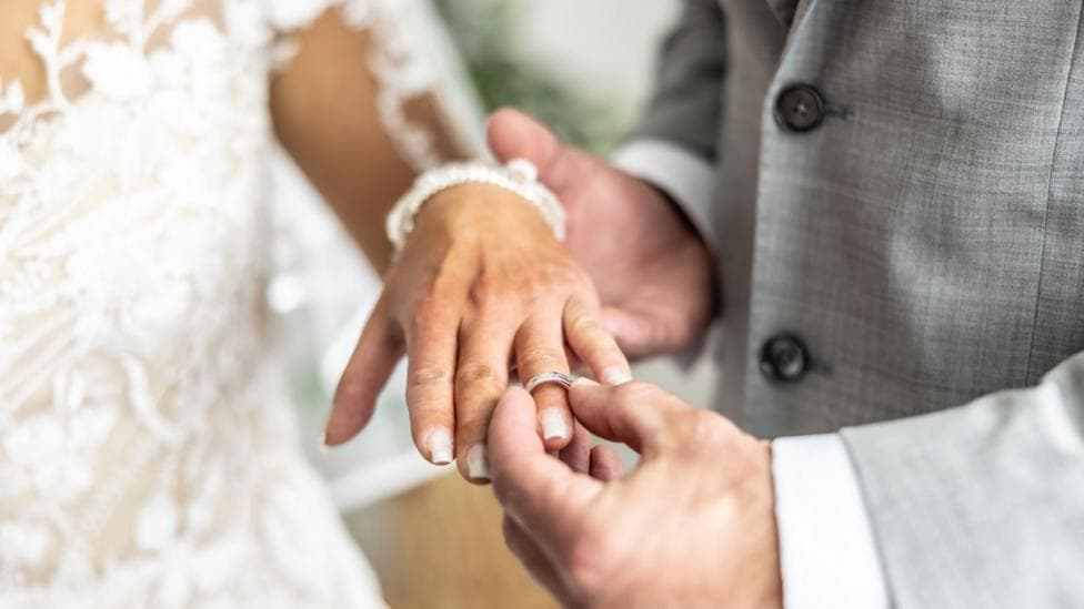 A man puts a ring on a bride's finger