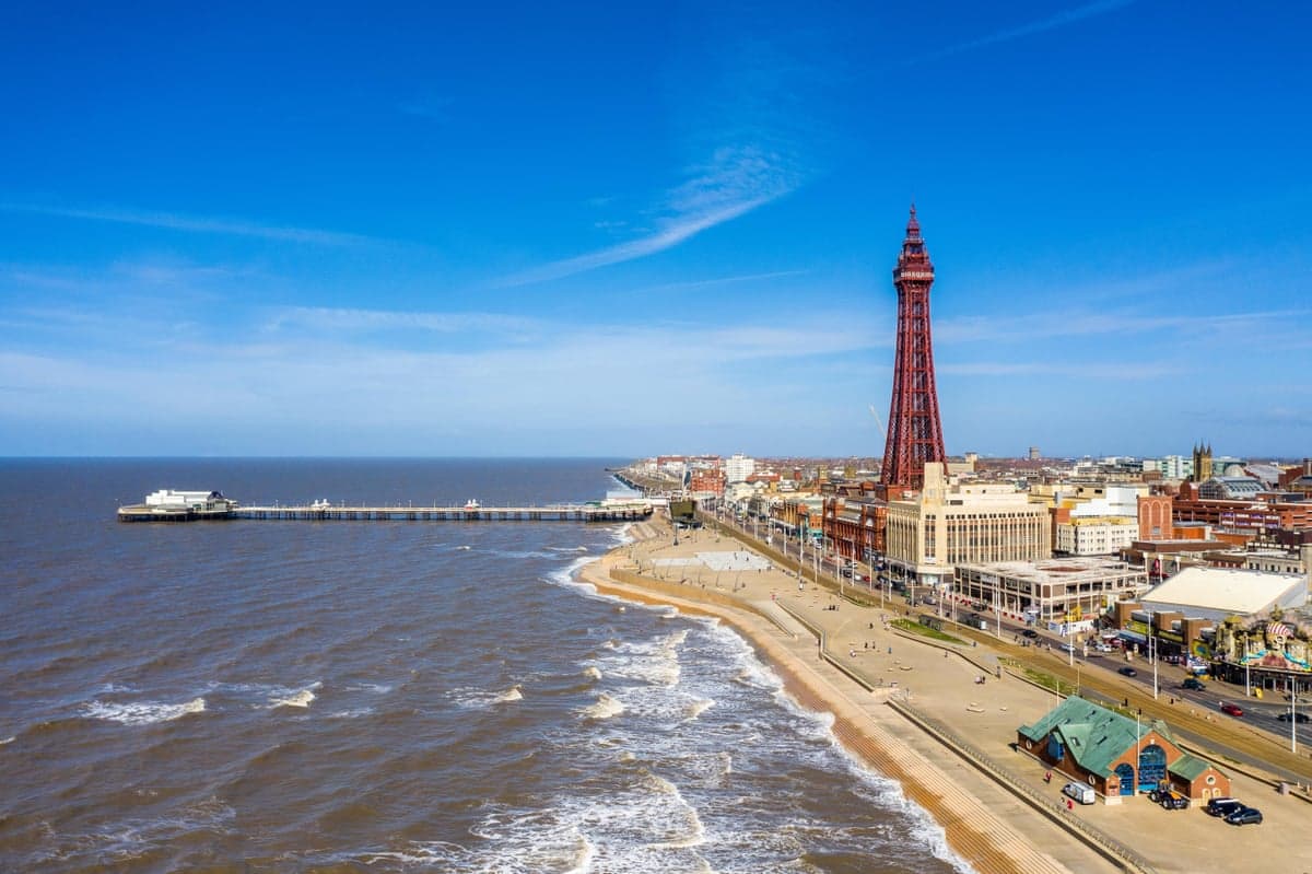 Aerial view of Blackpool Tower, pier and promenade along the beach and ocean waves
