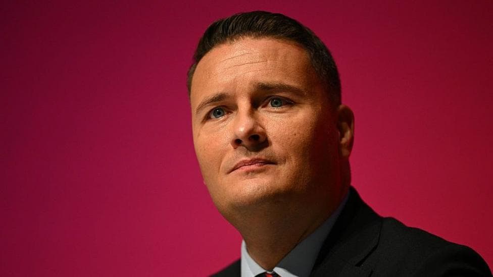 Defence Secretary Wes Streeting speaking with a pink background behind him
