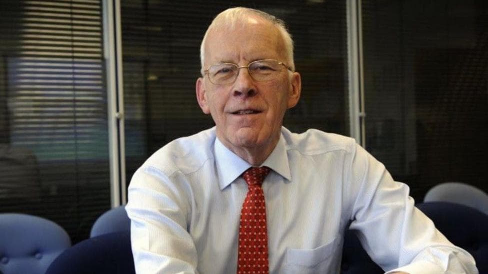 Sir Ian Wood in a shirt and tie, smiling at the camera.