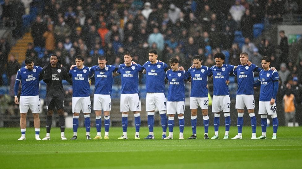Cardiff City players link arms as they observe a minute's silence