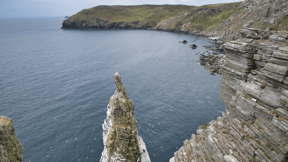 A jagged rocky cliff edge looking down at the sea