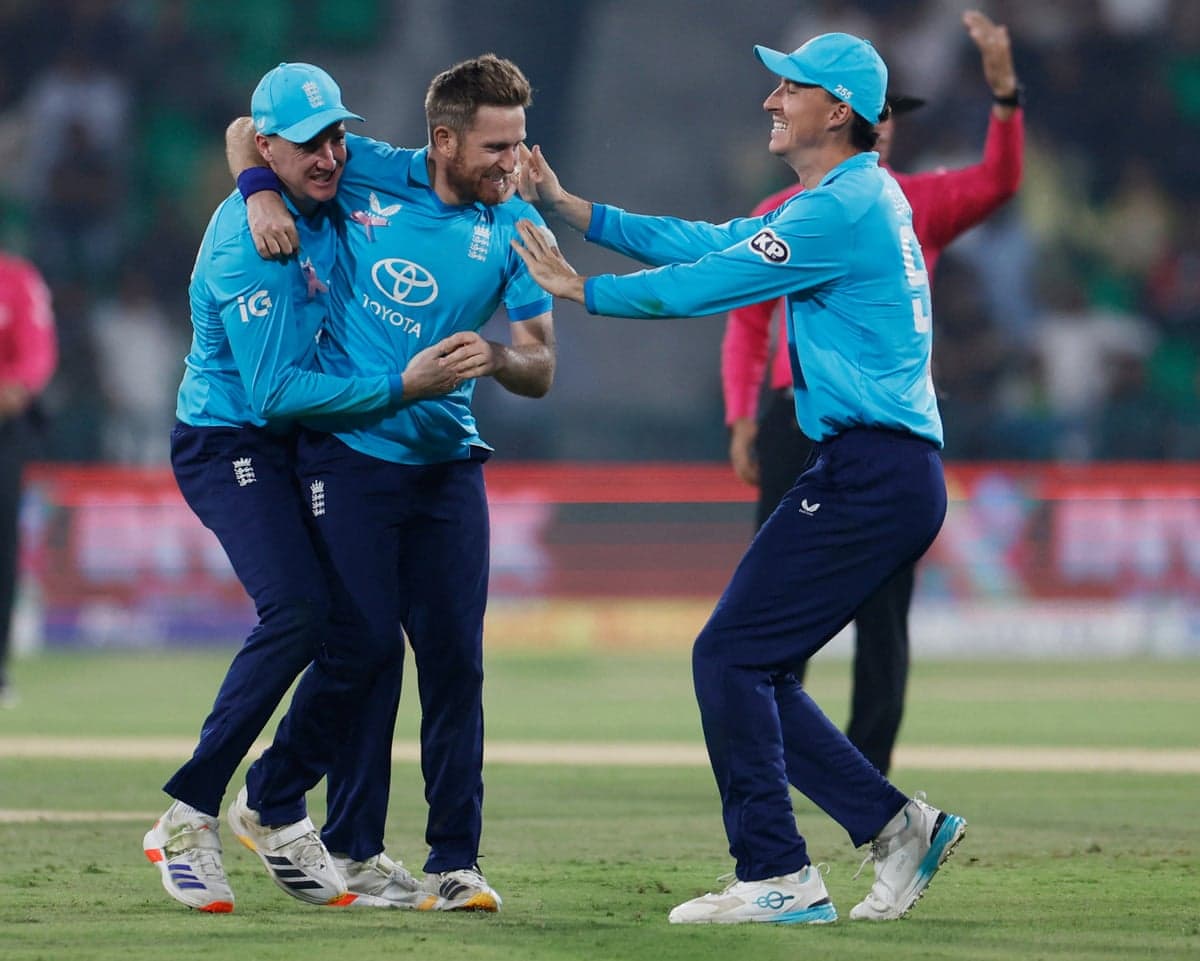 England's Liam Dawson celebrates a wicket with teammates on the cricket pitch.
