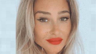 Joanna Derkacz smiles at the camera in a close-up photo. She has long, blonde hair and wears eye make-up and red lipstick.