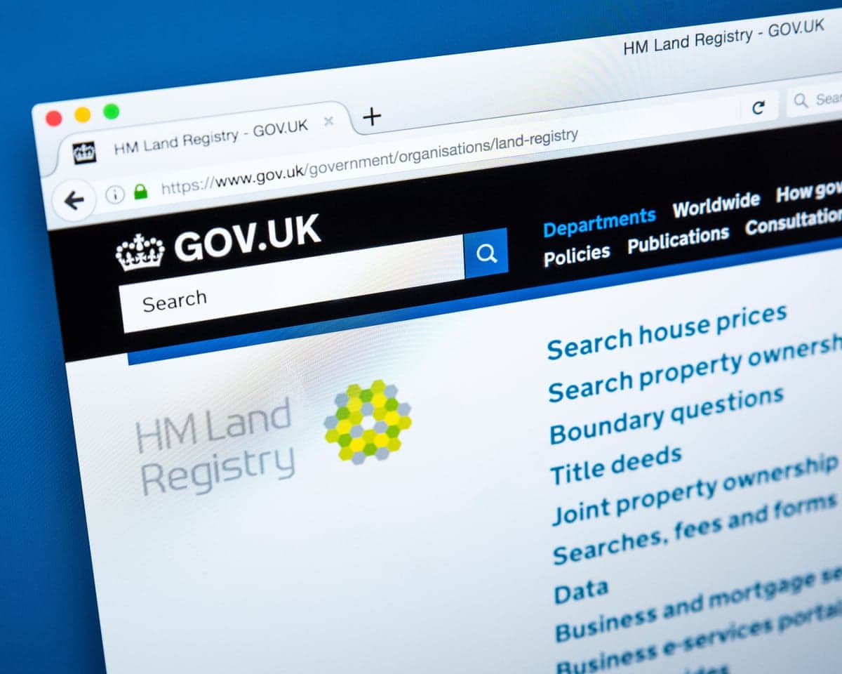 A close-up of a computer screen showing the GOV.UK HM Land Registry homepage with a menu list