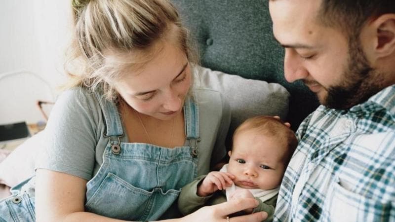 A young woman and a man with a baby in the middle of them.