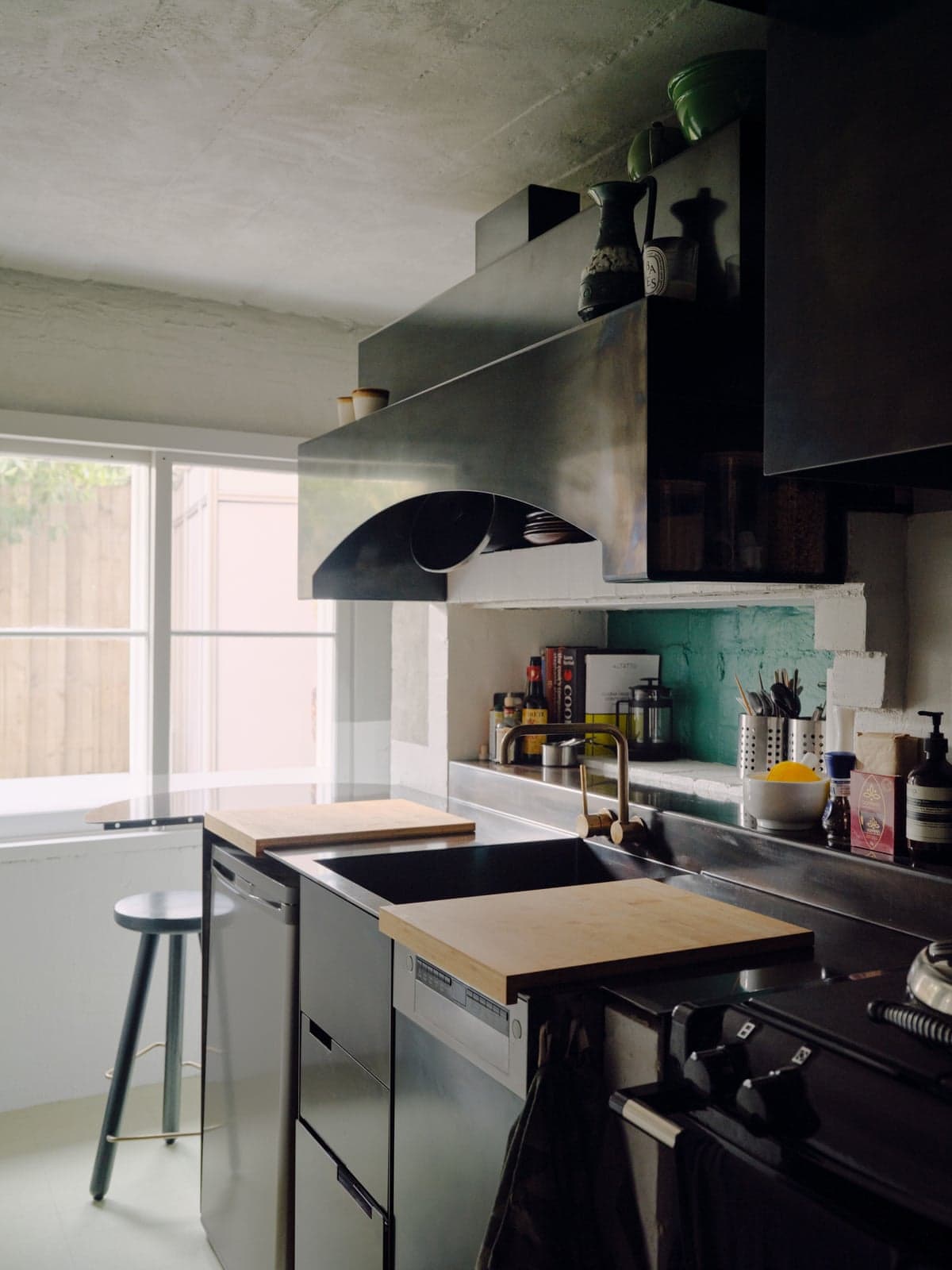 The Studio8 apartment's small kitchen with a dark metal extractor hood, steel counters and wooden chopping boards
