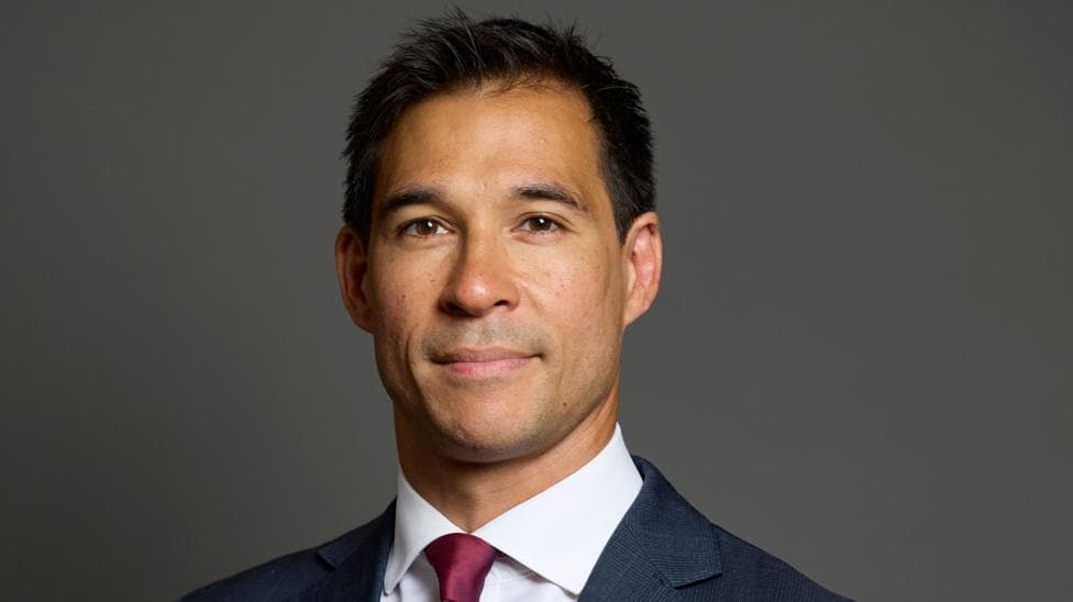 A politician. He is wearing a dark blue suit and has a red tie.