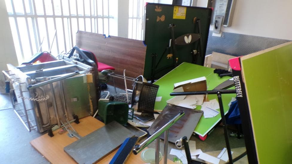A collection of broken furniture inside a prison hall at HMP Polmont