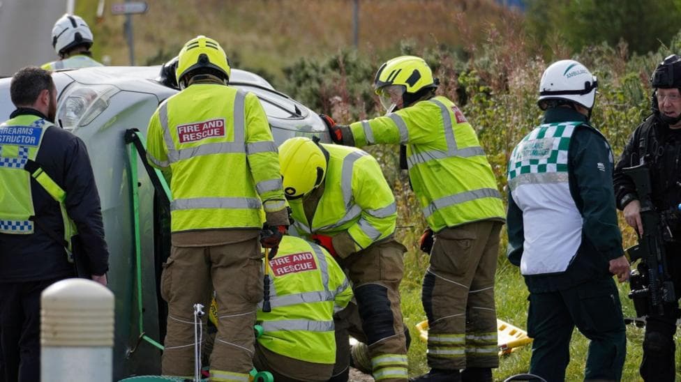 Firefighters along with armed police at the scene of a crashed car in the training exercise