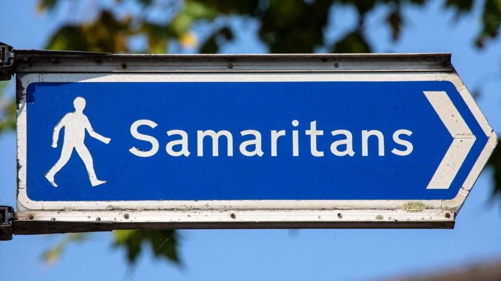 A blue sign with a the word "Samaritans" in white letters and a white figure walking.