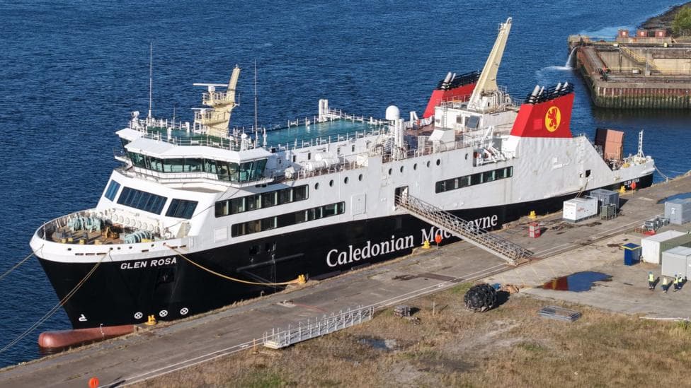 A large black and white ship with red funnels moored at a quayside