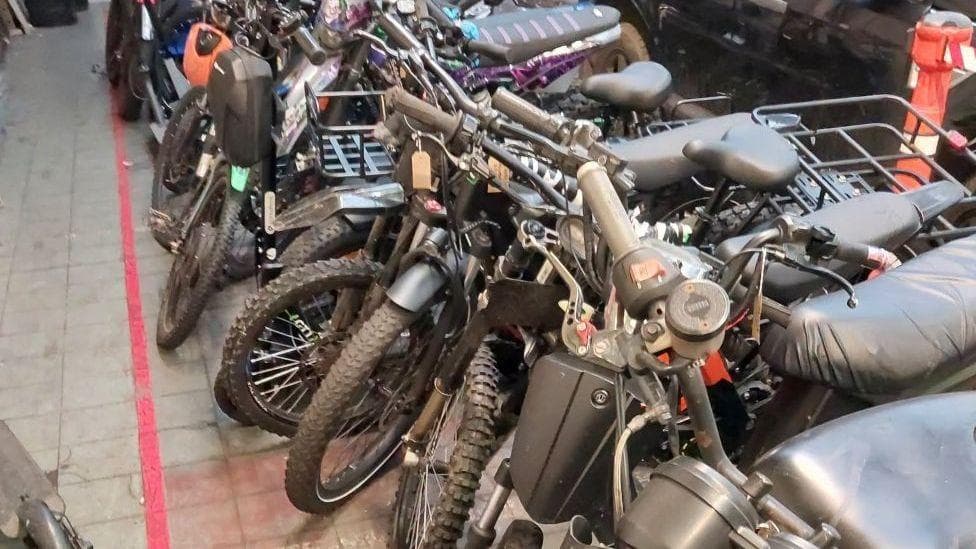Several motorbikes of various types lines up after being seized by police.
