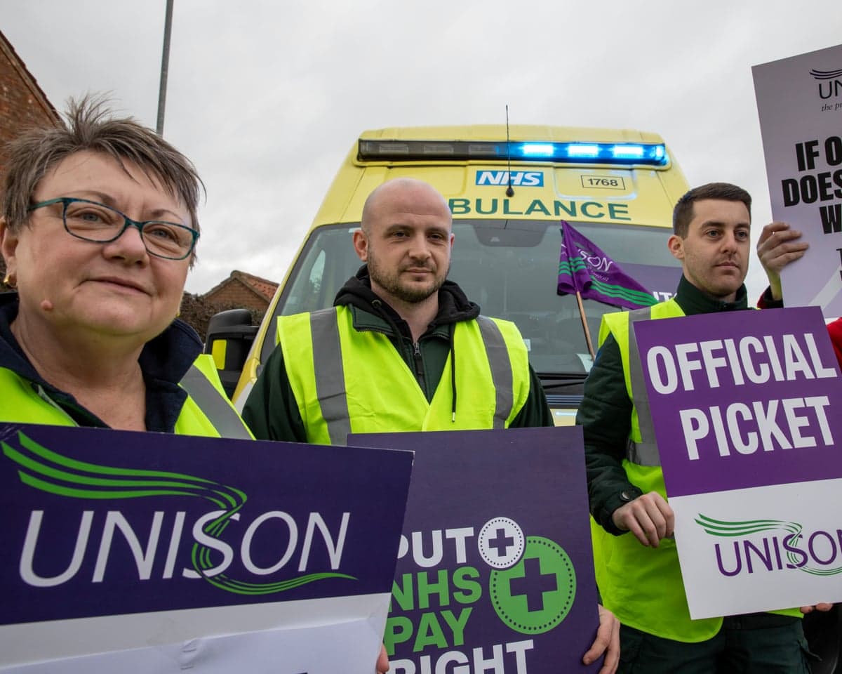 Ambulance workers and paramedics on the picket line, holding up official Unison signs