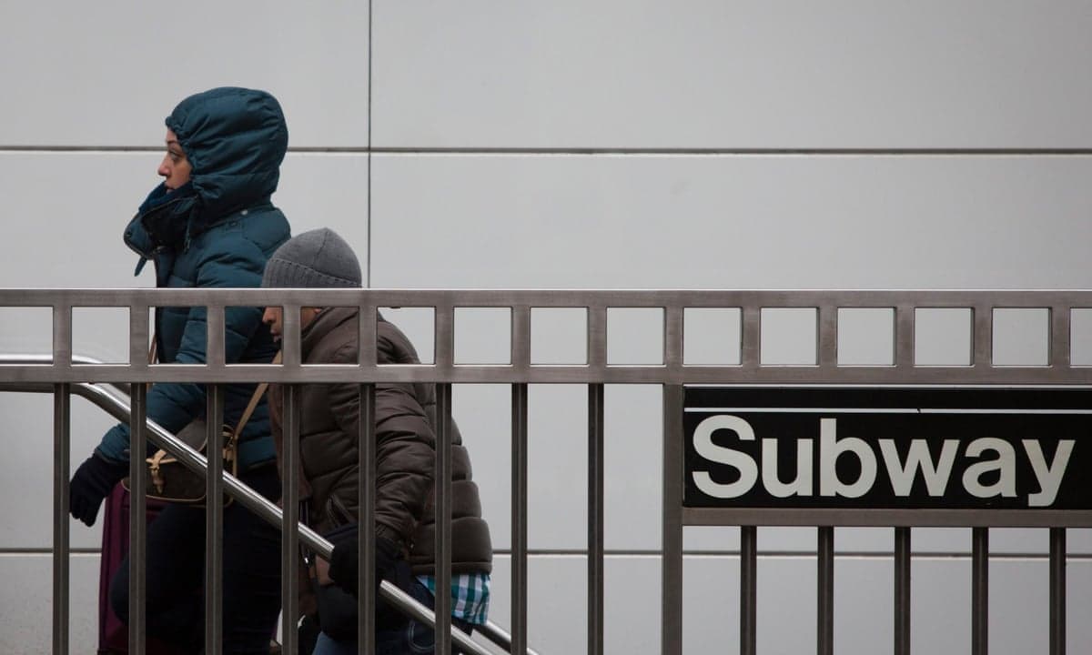 people in warm coats come out of the new york subway