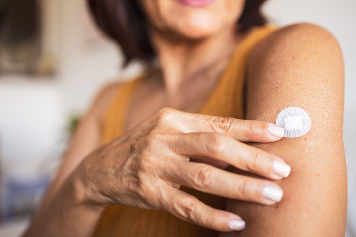 A woman sticks a transdermal patch on the skin