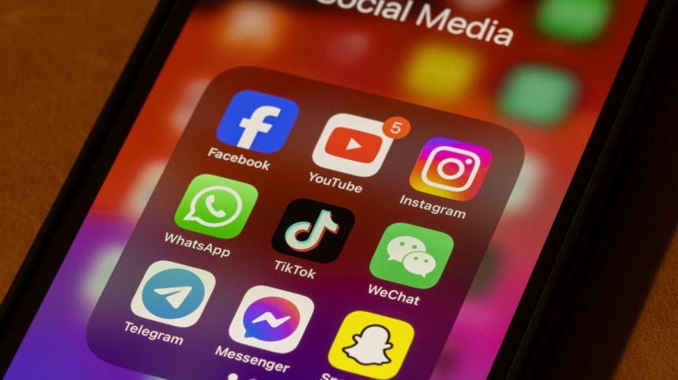 A picture of someone’s mobile phone close up. A number of social media app icons are visible on the homepage, such as Snapchat and Instagram.