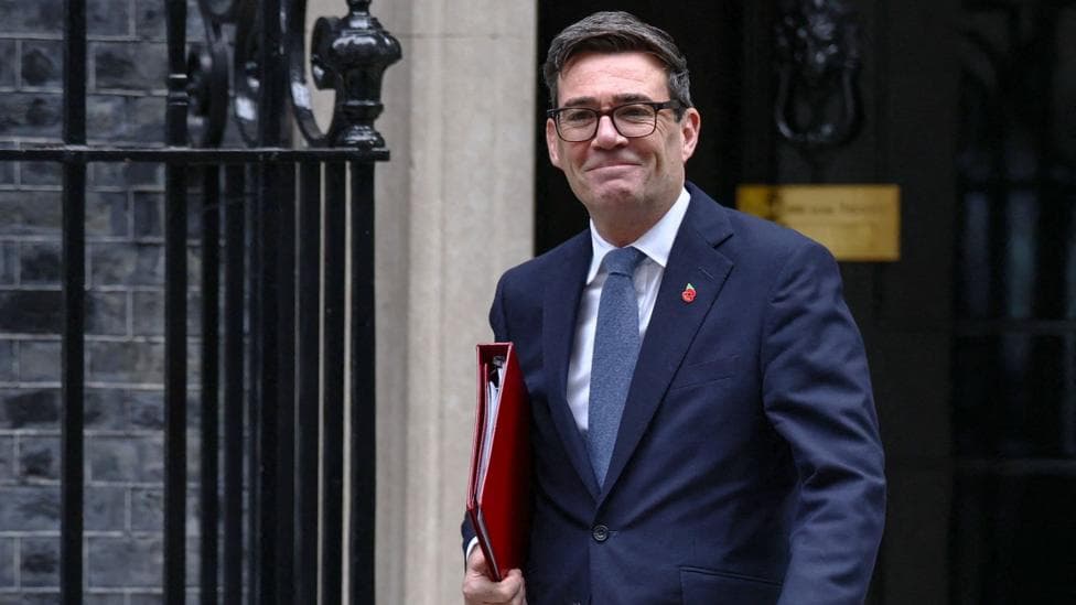 Andy Burnham smiling and walking out of number 10 Downing street with a red book under his arm